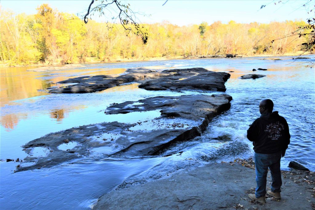 Hiker at fish traps rock formation on Cape Fear River at Raven Rock State Park