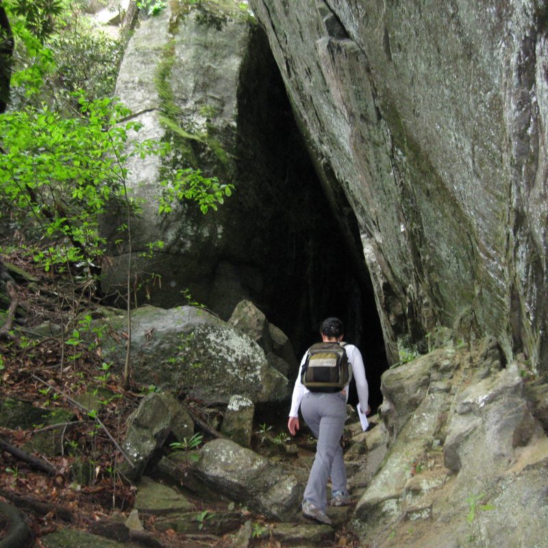 Woman approaching Little Bat Cave in Hickory Nut Gorge, North Carolina