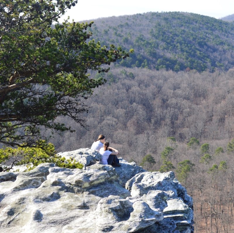 Couple sitting on rock at peak of Hanging Rock in Hanging Rock State Park, Danbury, North Carolina