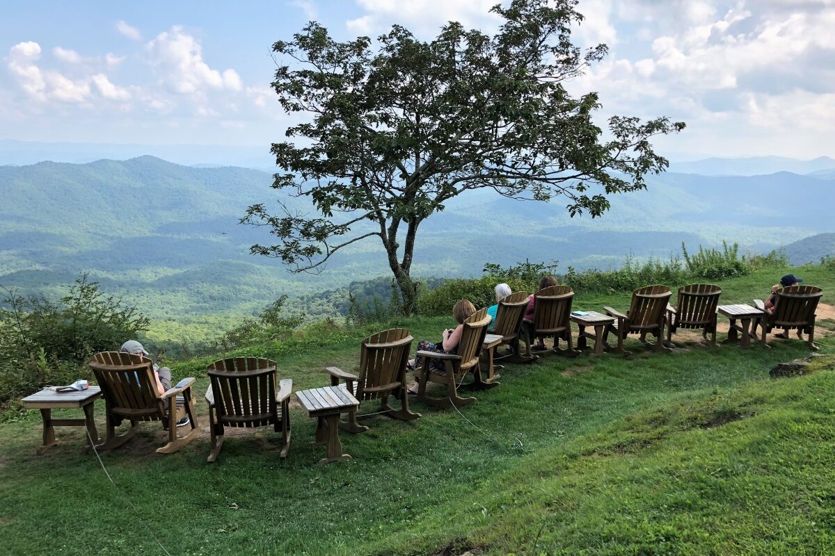 People in Adirondack chairs looking out over valley from ridge at Pisgah Inn on the Blue Ridge Parkway
