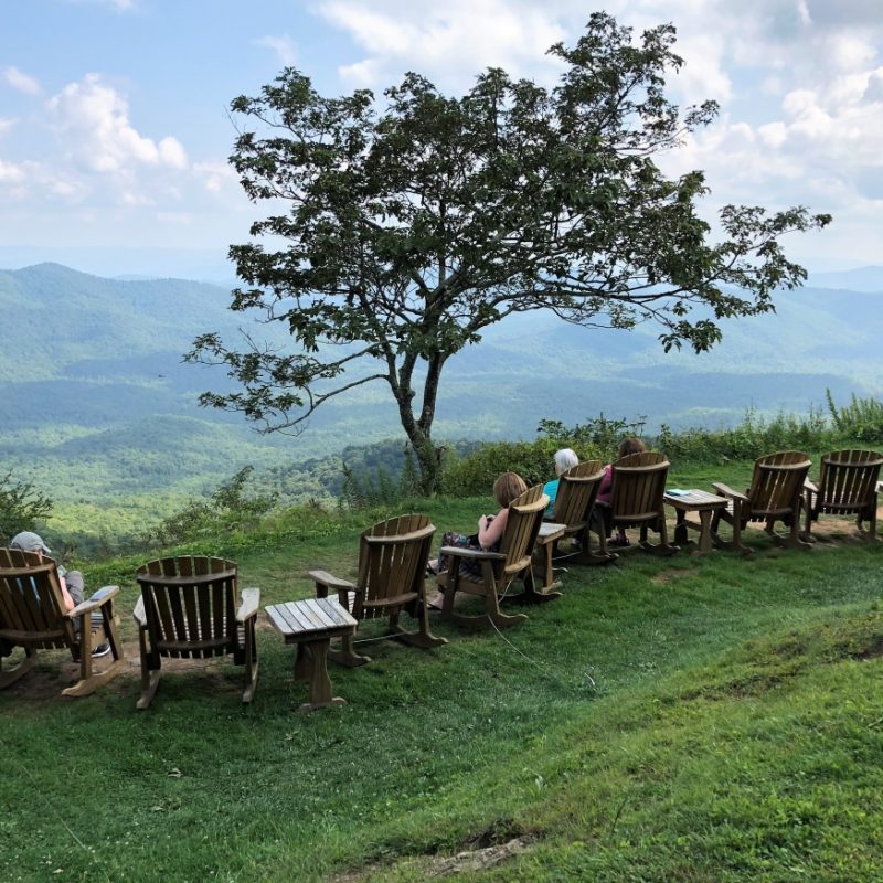 People in Adirondack chairs looking out over valley from ridge at Pisgah Inn on the Blue Ridge Parkway