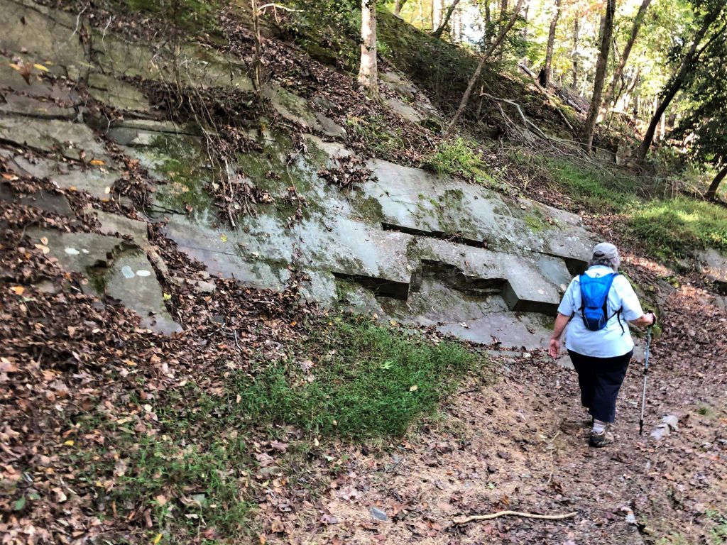 depict hiker next to wall of stone on Quarry Trail at Morrow Mountain State Park