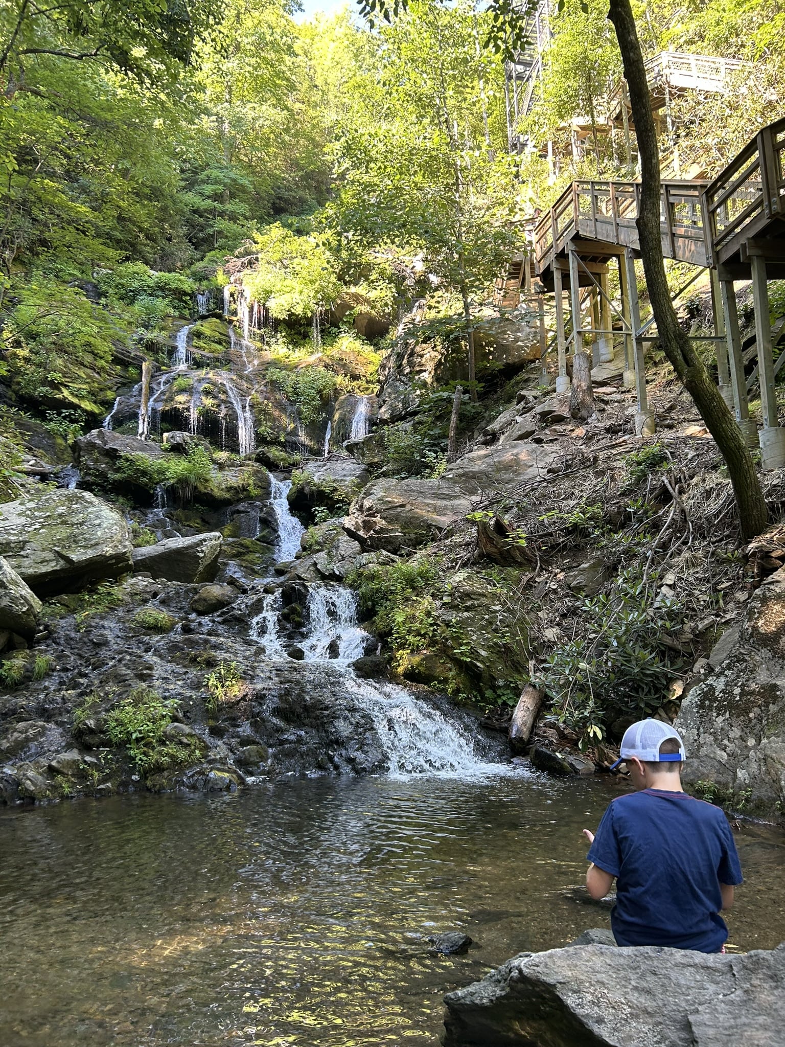 boy at base of waterfall in forest