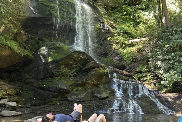 couple lying on rock at baseof waterfall in forest